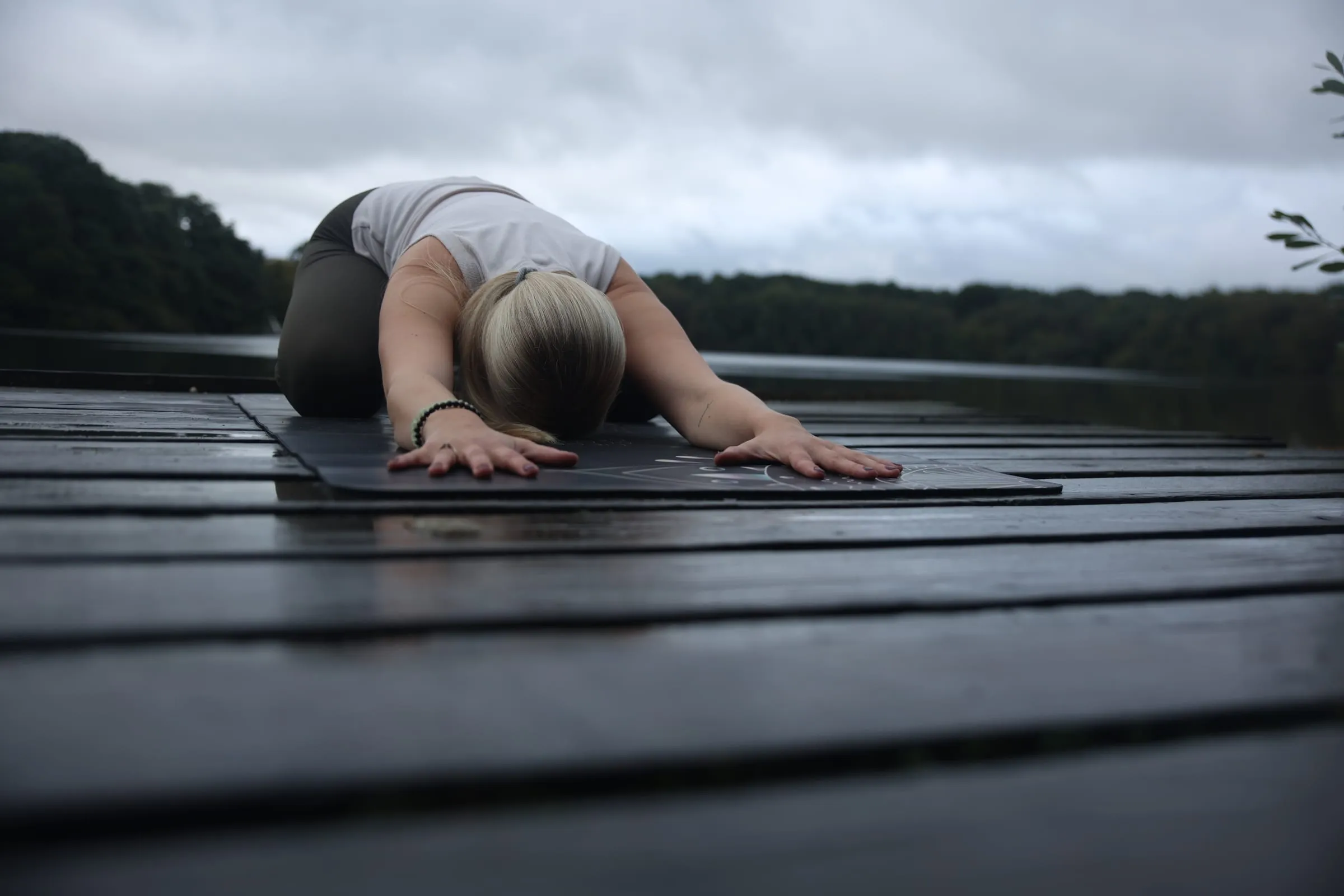 Katrin ruht in der Haltung des Kindes auf einem Holzsteg am See